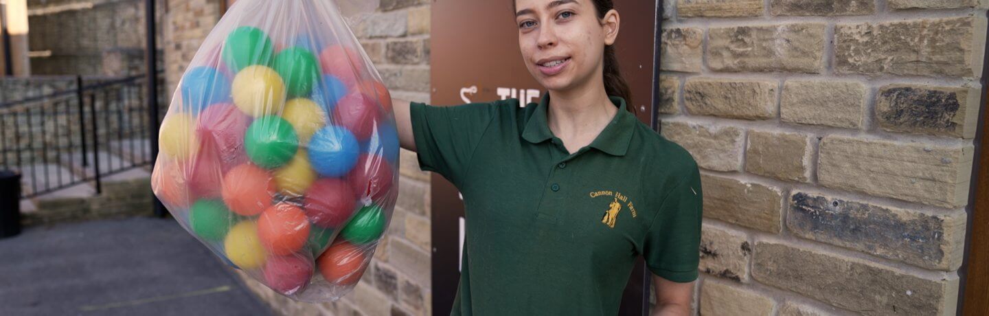 Photo of Kate holding a sack of plastic multi coloured toy balls which will create a ball-pit for the meerkats